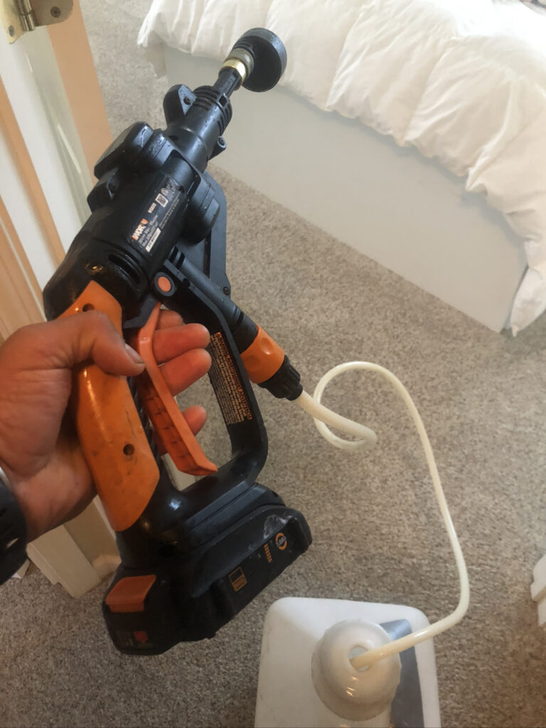 Hand holding a cordless power tool indoors.
